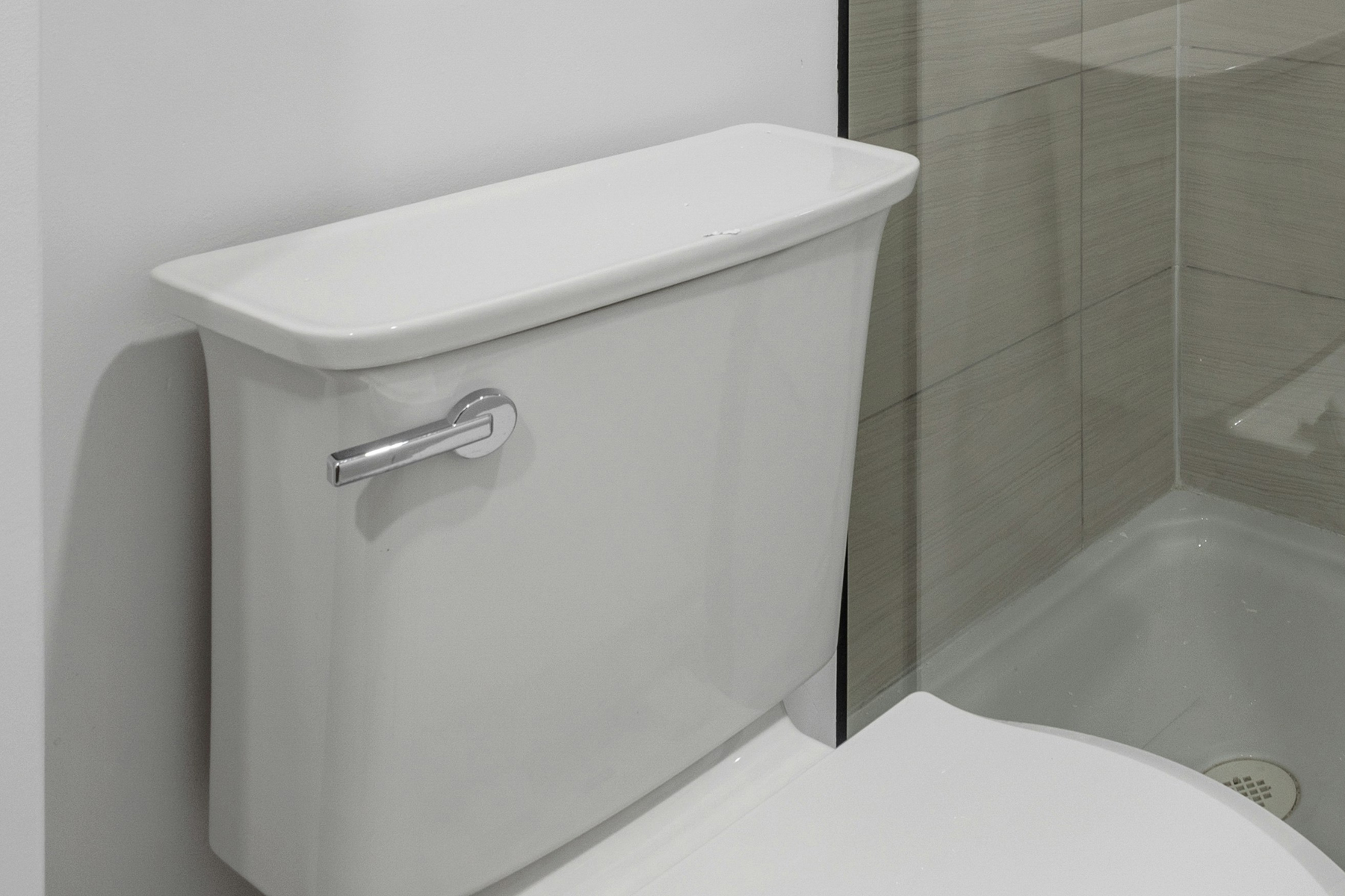 Weißer Spülkasten auf einer Toilette in hellem Badezimmer